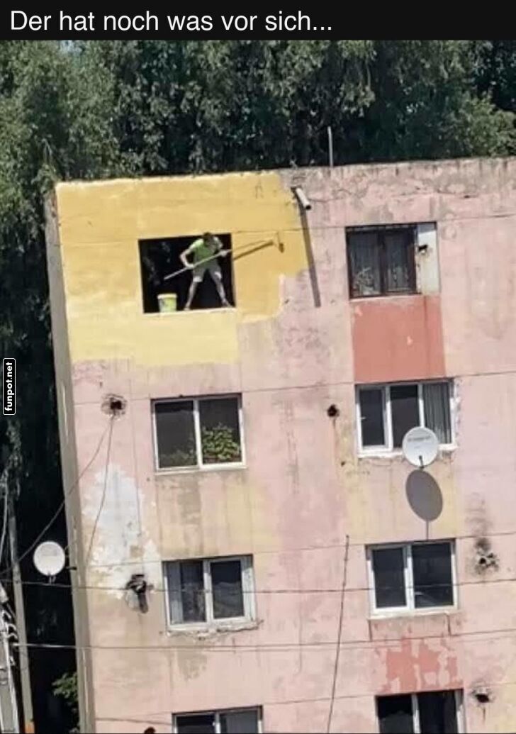 Mann malt Gebäude von Innenfenster aus Mann malt Gebäude von Innenfenster aus