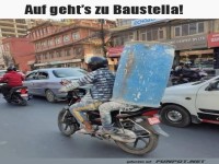 Motorradfahrer mit Baumaterial auf dem Weg