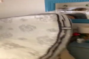 Frau schneidet Matratzenverpackung auf